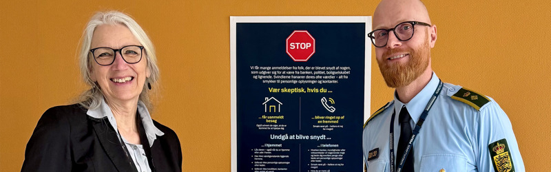 Centerchef Jytte Thøgersen og politikommissær Philip Larsen står med en plakat, der skal advare om svindel af ældre og sårbare i deres hjem