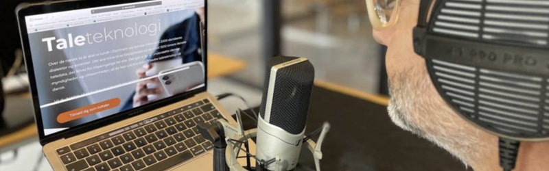 Foto af person med headset, der læser op fra en computerskærm til mikrofon