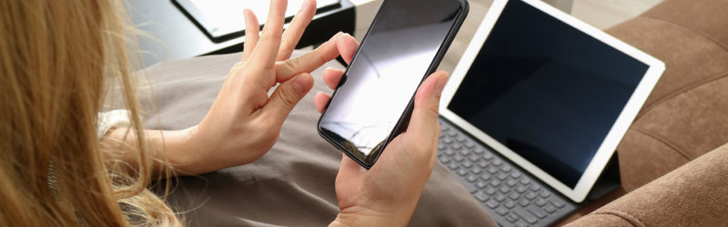 Foto af kvinde, der sikker med mobiltelefon og bærbar computer.